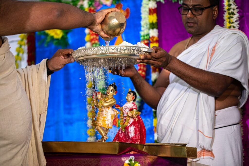 Pandits performing abhishekam with metal tray