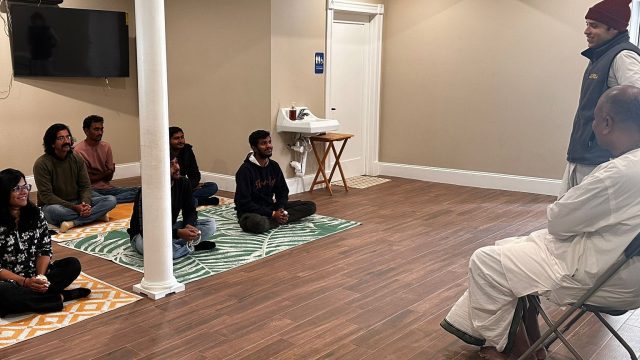 Devotees sitting on floor mats during a class